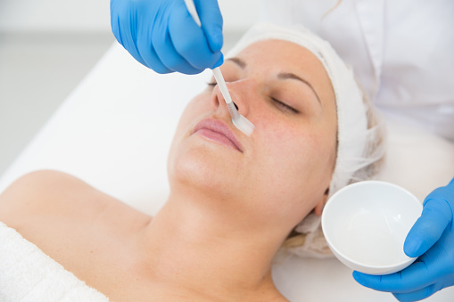 Beautician Brushing Chemical Peel Solution On Woman's Face Stock Photo