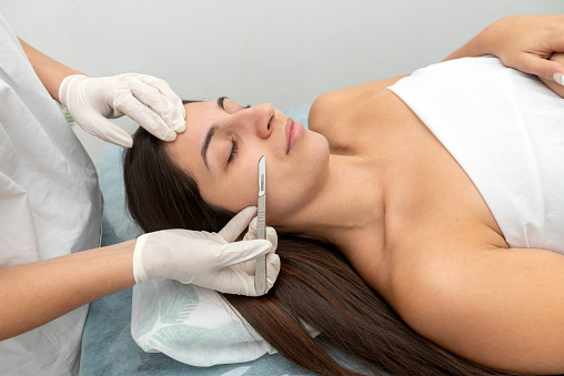 A Hispanic female patient with eyes closed in the cosmetic clinic preparing for dermaplaning treatment